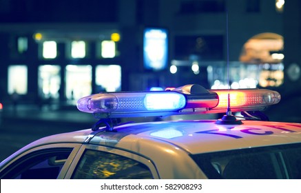 Мигалка синего света на полицейской машине. Городские огни на заднем плане.