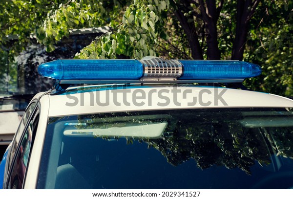 A blue light on top of a police car on a summer\
sunny day. No people