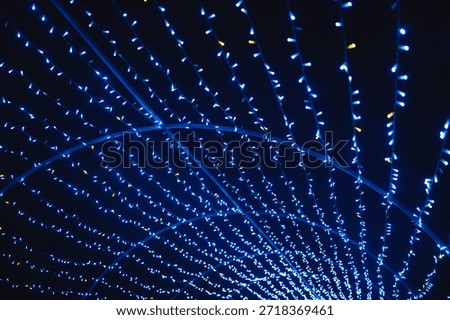 Blue light strings curve over dark background creating an abstract tunnel effect with small glowing bulbs.