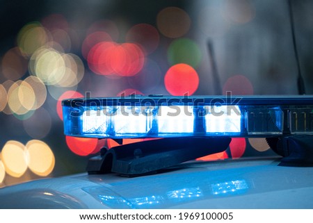 Blue lights on the roof of a police car with the background out of focus and lights with bokeh effect	
