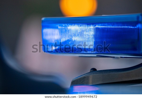 Blue lights on the roof of a\
police car with the background out of focus and lights with bokeh\
effect