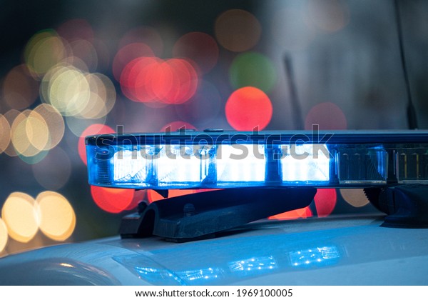 Blue lights on the roof\
of a police car with the background out of focus and lights with\
bokeh effect	\
