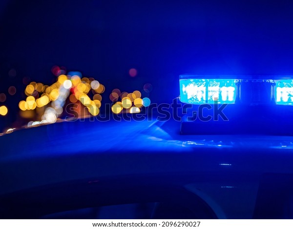 Blue lights on the roof of a\
police car with the background out of focus and lights with bokeh\
effect