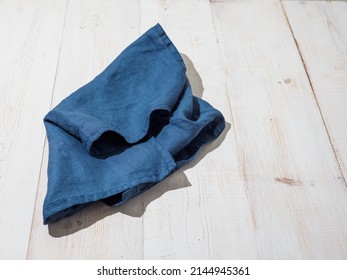 Blue linen kitchen towel or textile napkin on white wooden background.