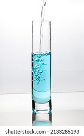 Blue Liquid Pouring Into Tall Glass On Bright Field High Key Background