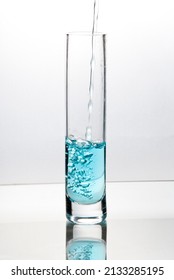 Blue Liquid Pouring Into Tall Glass On Bright Field High Key Background