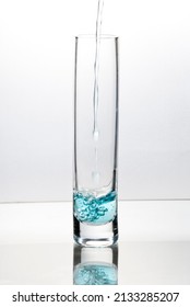 Blue Liquid Pouring Into Tall Glass On Bright Field High Key Background