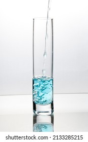 Blue Liquid Pouring Into Tall Glass On Bright Field High Key Background