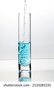 Blue Liquid Pouring Into Tall Glass On Bright Field High Key Background