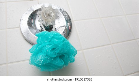 A Blue Loofah Sponge Hanging In A Wet Shower On The Temperature Guage.