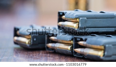 Blue magazines with bullets of firearm putted on wooden table. Ammunition for protection of soldiers. Close up view, blurred background.
