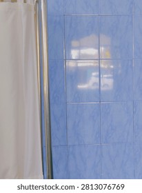 Blue marble pattern ceramic wall tiles inside bathroom next to white shower curtain