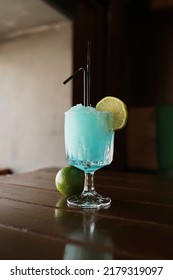 A Blue Margarita Cocktail With A Slice Of Lime Is On The Table. The Composition Of The Cocktail Includes Tequila, Blue Curacao Liqueur, Margarita Mix