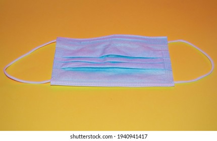 Blue Mask On A Yellow Background In The Foreground, Surgical And Breathable Mask To Protect Against Viruses.