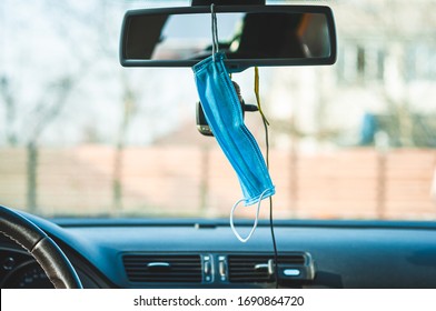 A blue medical antibacterial mask is hanging in the car's interior on a mirror in front of the DVR.