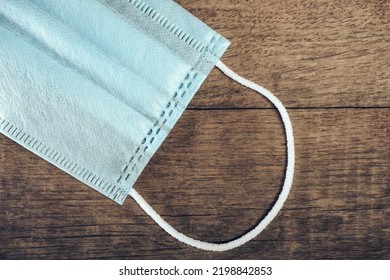 Blue Medical Mask Lies On A Old Brown Wooden Table Background Texture.