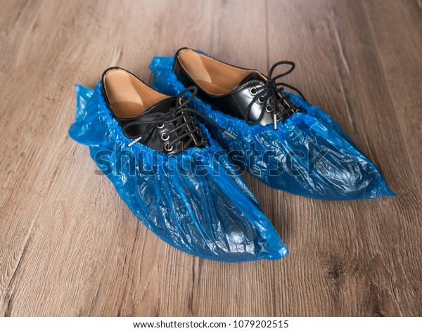 Blue medical shoe covers are worn\
over shoes on the floor, leather mens shoes in overshoes, bahily on\
the boots, hygiene and cleanliness in medical\
institutions