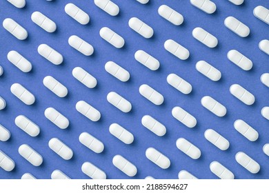 Blue medicine background with white pills and tablet, macro. Drug production backdrop. Medical pattern from vitamin capsule, closeup. - Shutterstock ID 2188594627