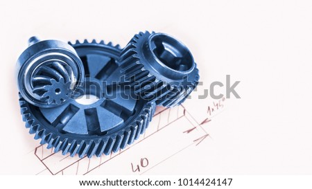 Blue metal gearwheels with a technical drawing in background. Abstract industrial background with mechanical engineering theme from cogwheels.