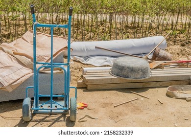 Blue metal hand truck with miscellaneous tools at construction site. - Shutterstock ID 2158232339