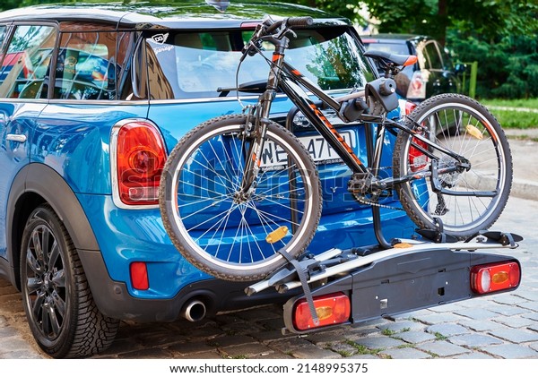 Blue Mini\
Cooper car with road bicycle loaded on rack, Road trip concept.\
Wroclaw, Poland - August 13,\
2021