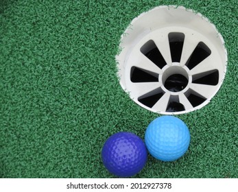 Blue Mini Putt Golf Balls Sitting Beside Hole On Green