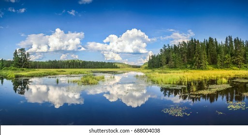 Blue Mirror Lake Reflections Of Clouds And Landscape. Ontario, Canada.