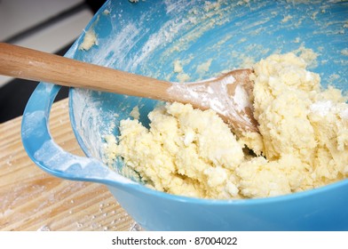 A Blue Mixing Bowl With Mixture And Wooden Spoon