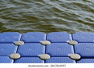 Blue modular plastic pontoon cubes forming a floating platform on calm water, providing a sturdy and stable surface for marine access