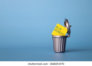 Blue Monday or Monday Blues concept. Wooden cube with text BLUE MONDAY inside dustbin, trash can. Copy space for text