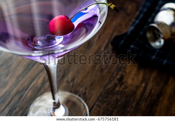 Blue Moon (aviation) Cocktail with cherry on\
wooden surface.