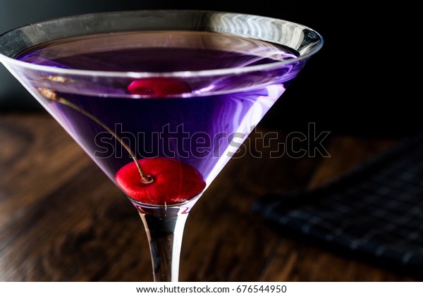 Blue Moon (aviation) Cocktail with cherry on wooden\
surface. 