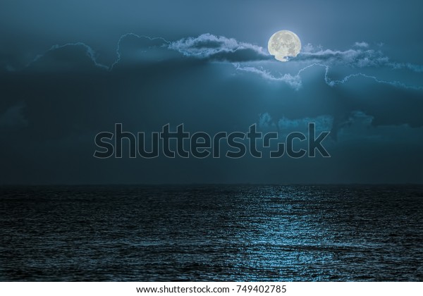 Blue moon light reflecting off ocean. Romantic\
twilight moonlight glistening off the surface of sea water. Lunar\
influence.