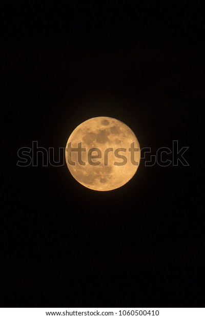 Blue Moon rising on 31 March 2018, photo\
dimensions, portrait orientated image with Moon isolated on black\
background with text or copy\
space.