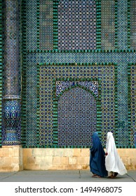 The Blue Mosque in Mazar-i-Sharif, Balkh Province in Afghanistan. Two women wearing burqas (burkas) walk past a wall of the mosque adorned with colorful tiles and mosaics. Northern Afghanistan. - Shutterstock ID 1494968075