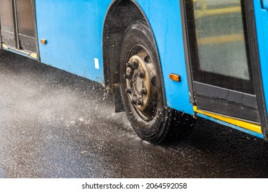 Blue Municipal Bus Moving On Rainy Road With Water Splashes - Close-up On Wheel