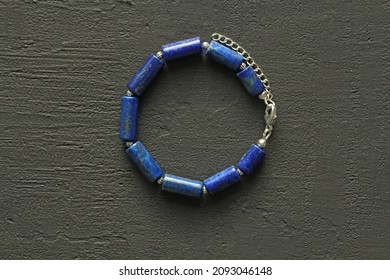 Blue natural lapis lazuli Bracelet made of natural stones lies on a black modern concrete background. Blue stone lapis lazuli. Handmade jewelry from natural stones. Handmade bracelets.