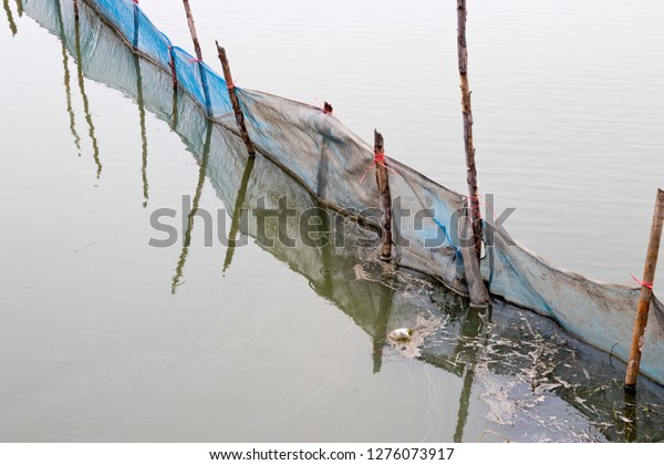 Blue net stretch across the canal to block drift\
trash and debris.