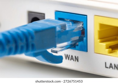 Blue network twisted pair cable connected to the WAN port on the modern wi-fi home router. Close up macro image.