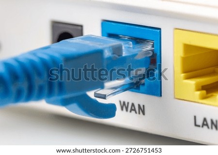 Blue network twisted pair cable connected to the WAN port on the modern wi-fi home router. Close up macro image.