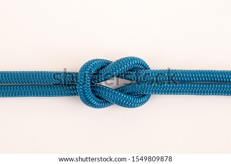 Blue nylon rope in square knot closeup on white