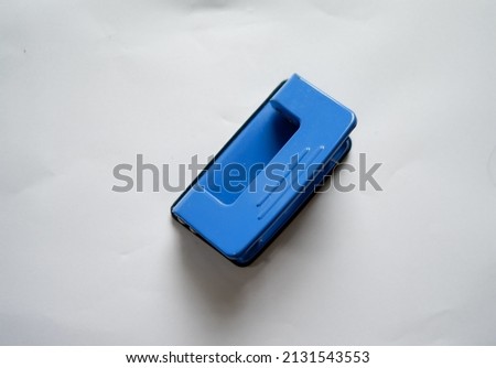 Blue office paper hole puncher on white background.