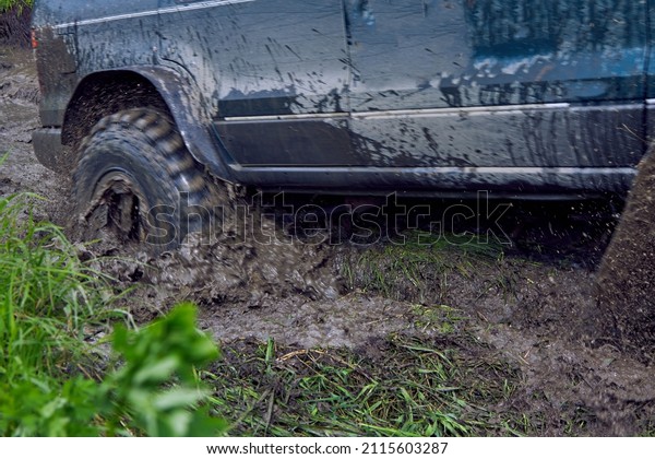 Blue offroader has\
stalled in the mud during an off-road race, the wheels are sliding\
on the slush. Racing through the woods and puddles. Blurry photo of\
a moving SUV