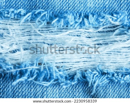 blue old denim fabric background with vertical torn lines striped texture of white fabric or close up torn denim use as backdrop