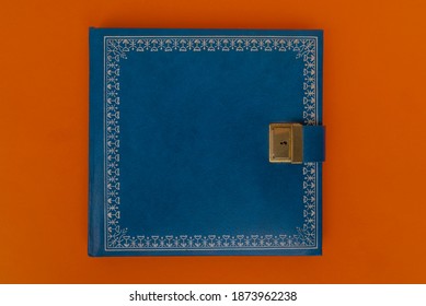 Blue Old Locked Diary Book Against Orange Background