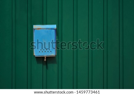 Blue old rusty mailbox on the green metal fence with a copy space