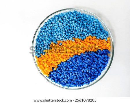 blue, orange masterbatch granules in laboratory pantry dish container isolated with white background, colorful polymer for product catalog design of industrial plastic manufacturing company profile