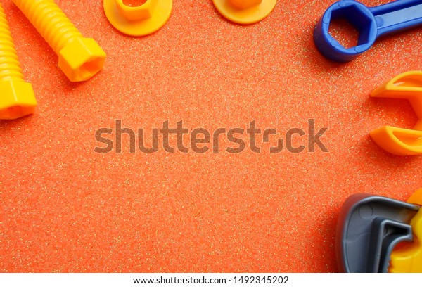 blue and orange toy tools on a dark\
orange background. wrenches and other toy\
tools