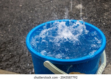 A Blue Pail Full with Blurry Water Splash from Rain During Monsoon Season