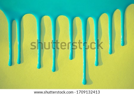 Blue paint flows down on a yellow background.